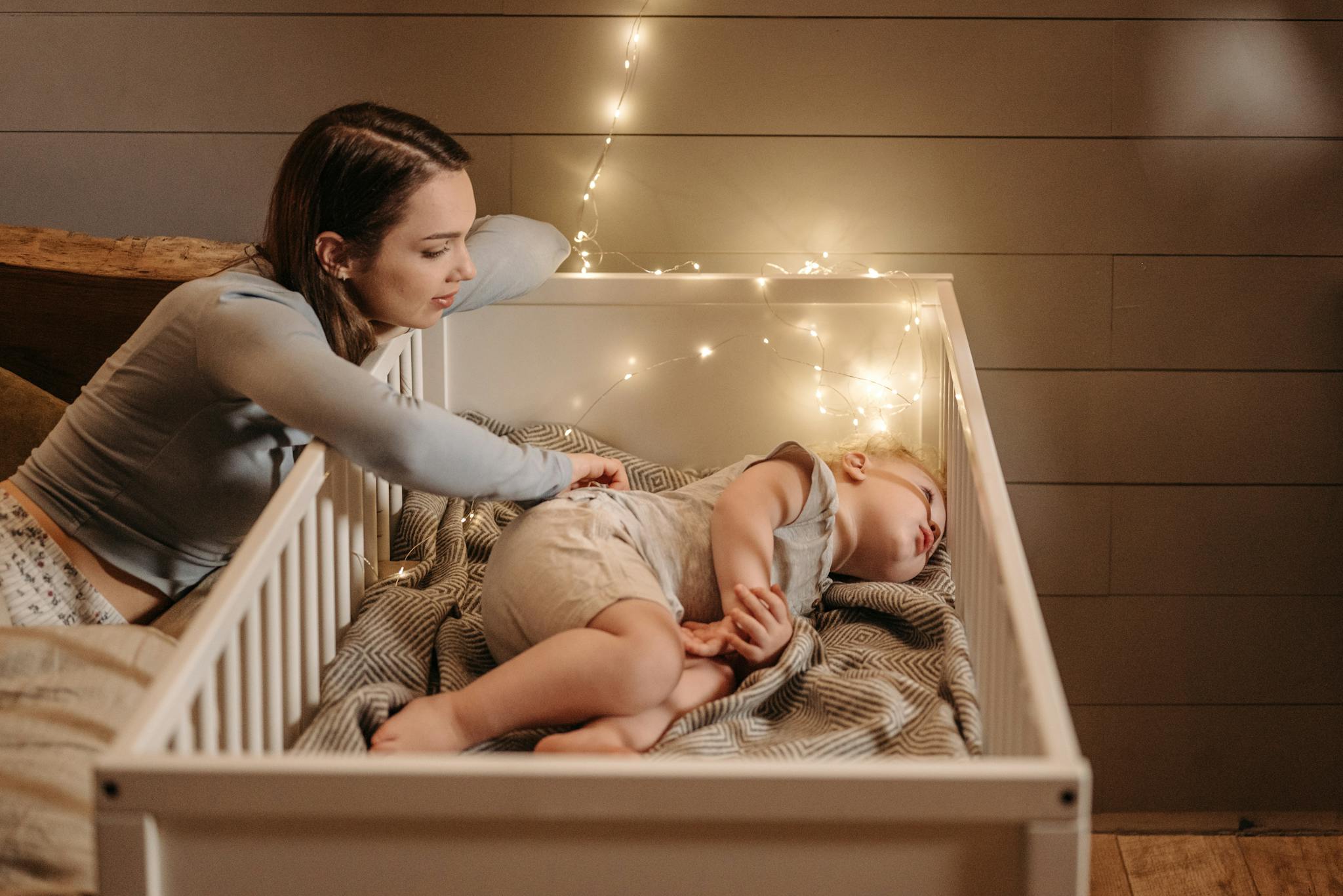 A Tender Moment Of A Mother Watching A tender moment of a mother watching over her sleeping baby in a warmly lit bedroom.