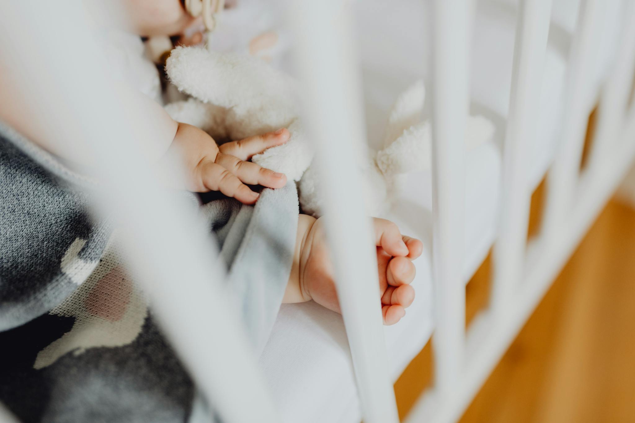 Adorable Baby Sleeping Peacefully In A Crib Adorable baby sleeping peacefully in a crib, holding a soft toy next to a baby blanket.
